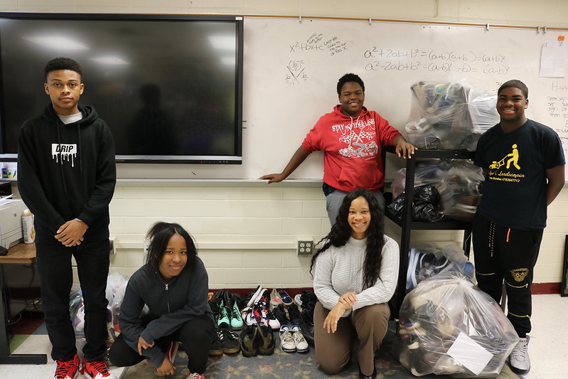 students stand in room with donated shoes